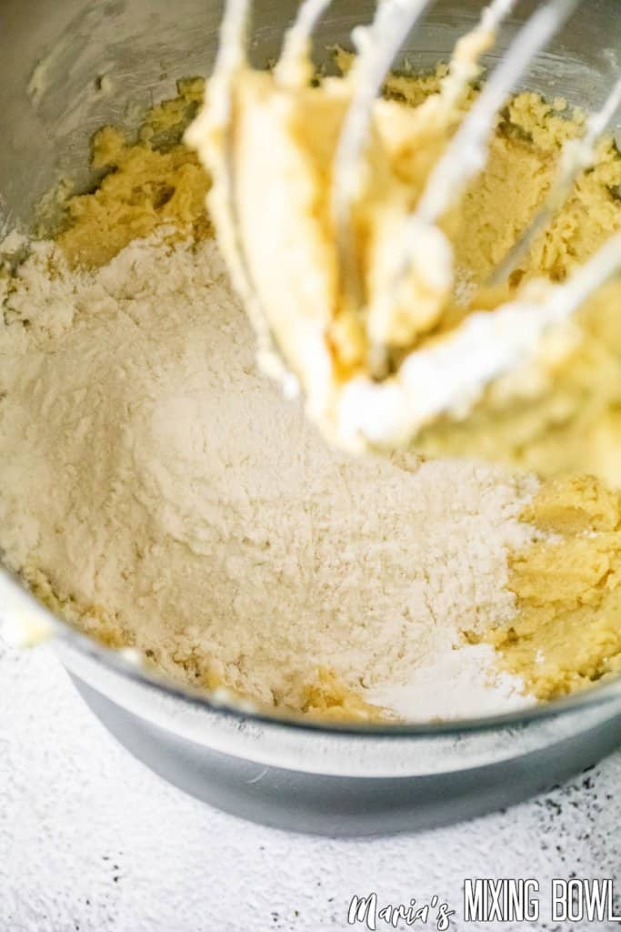flour being added to dough in a stand mixer