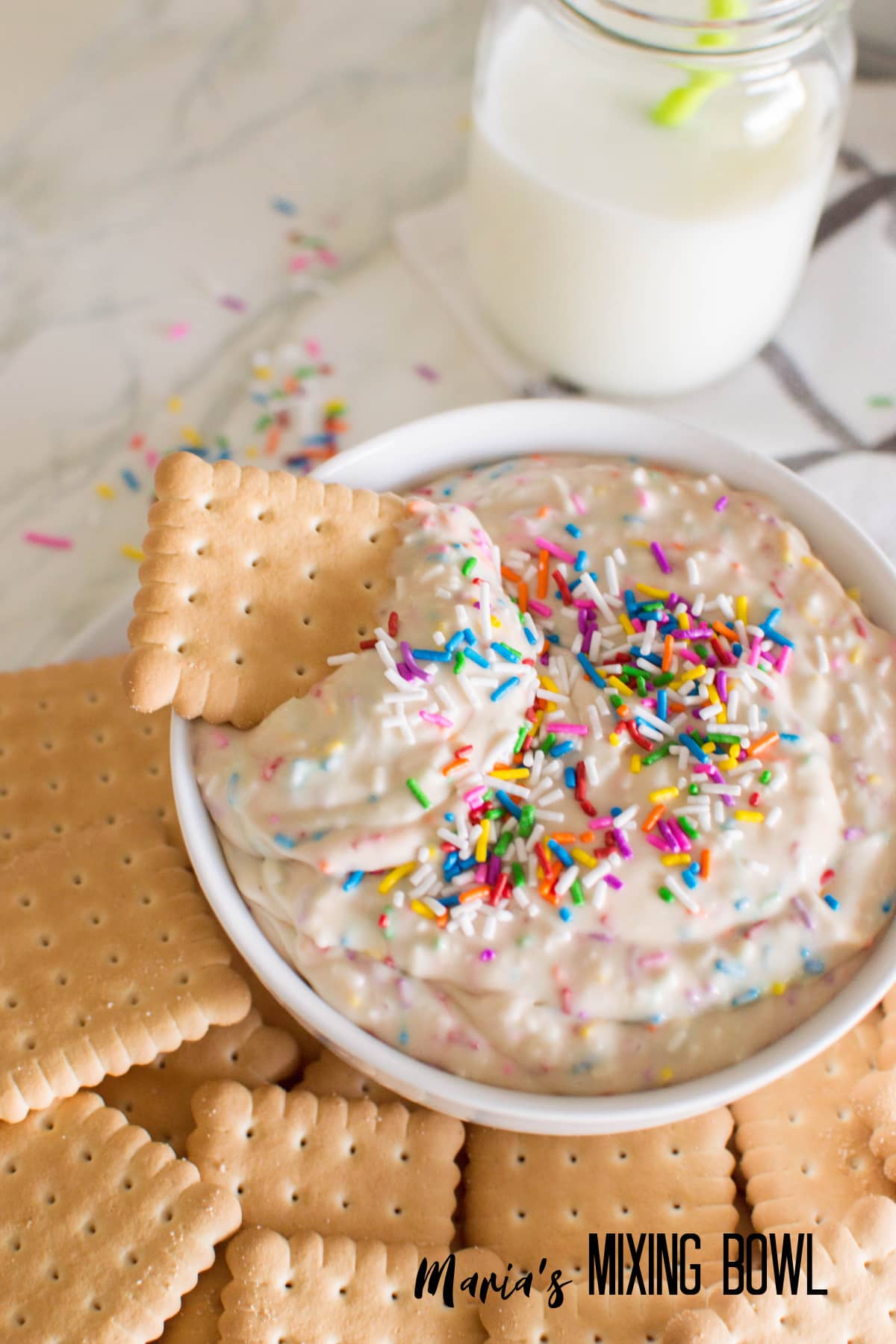 off center bowl of funfetti dip with a cookie diped in it.