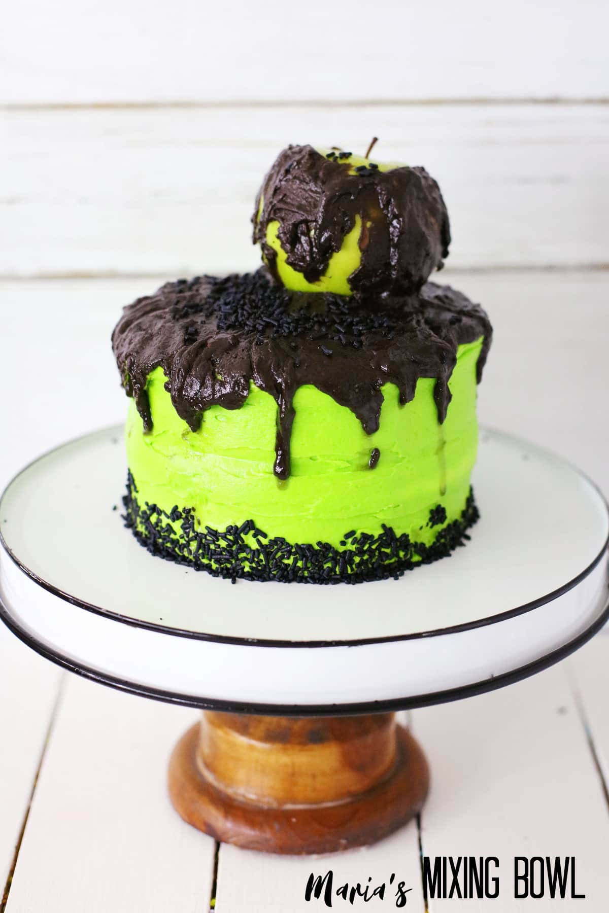 uncut poison apple cake on a black and white cake stand