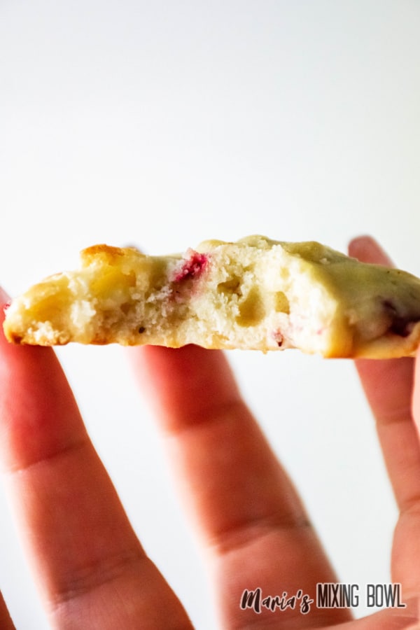 strawberry cheesecake cookie held in the air with a bite missing