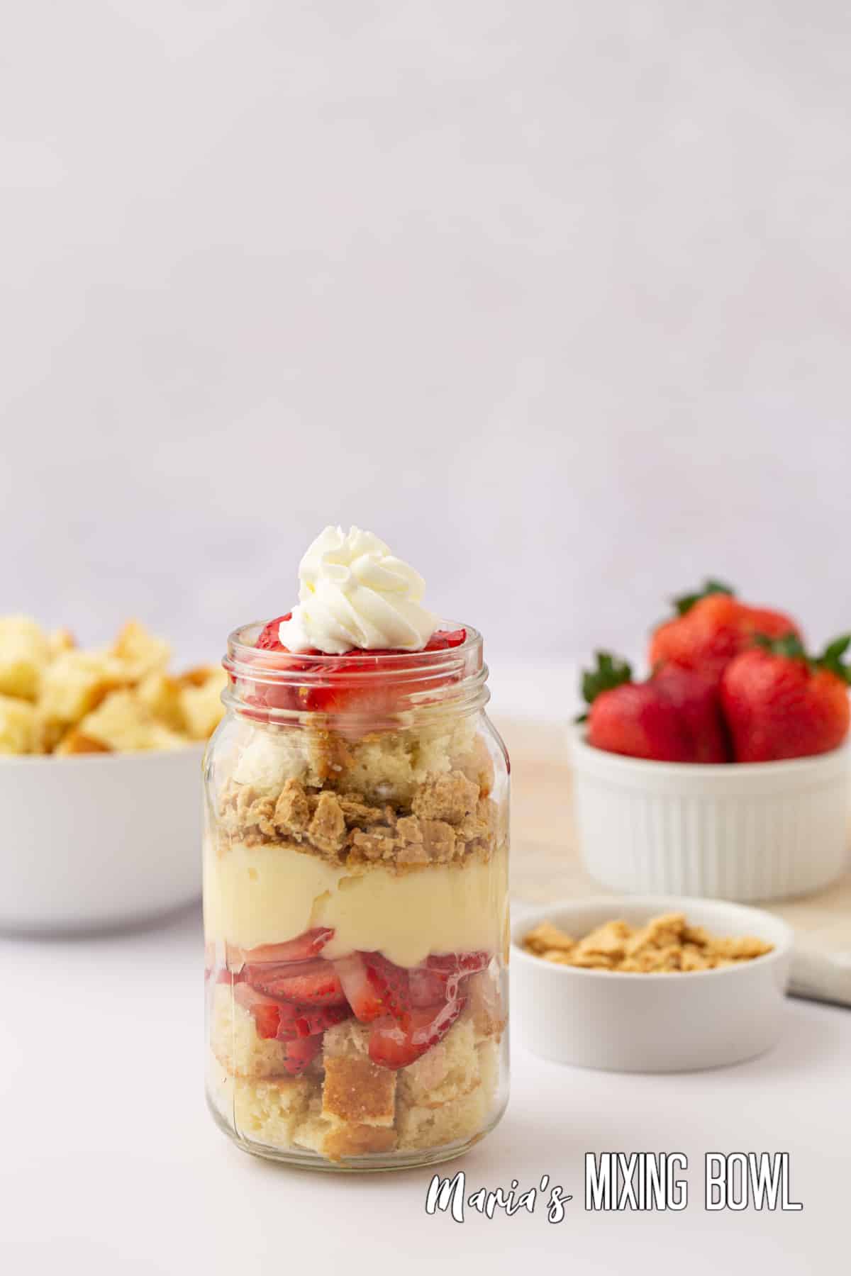 close up of strawberry cheesecake trifle in a mason jar