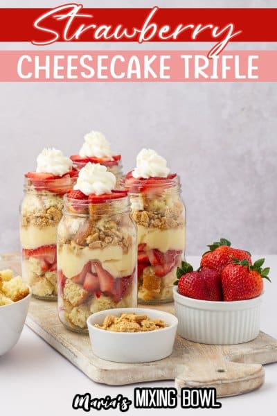 four strawberry cheesecake trifles on a wooden cutting board