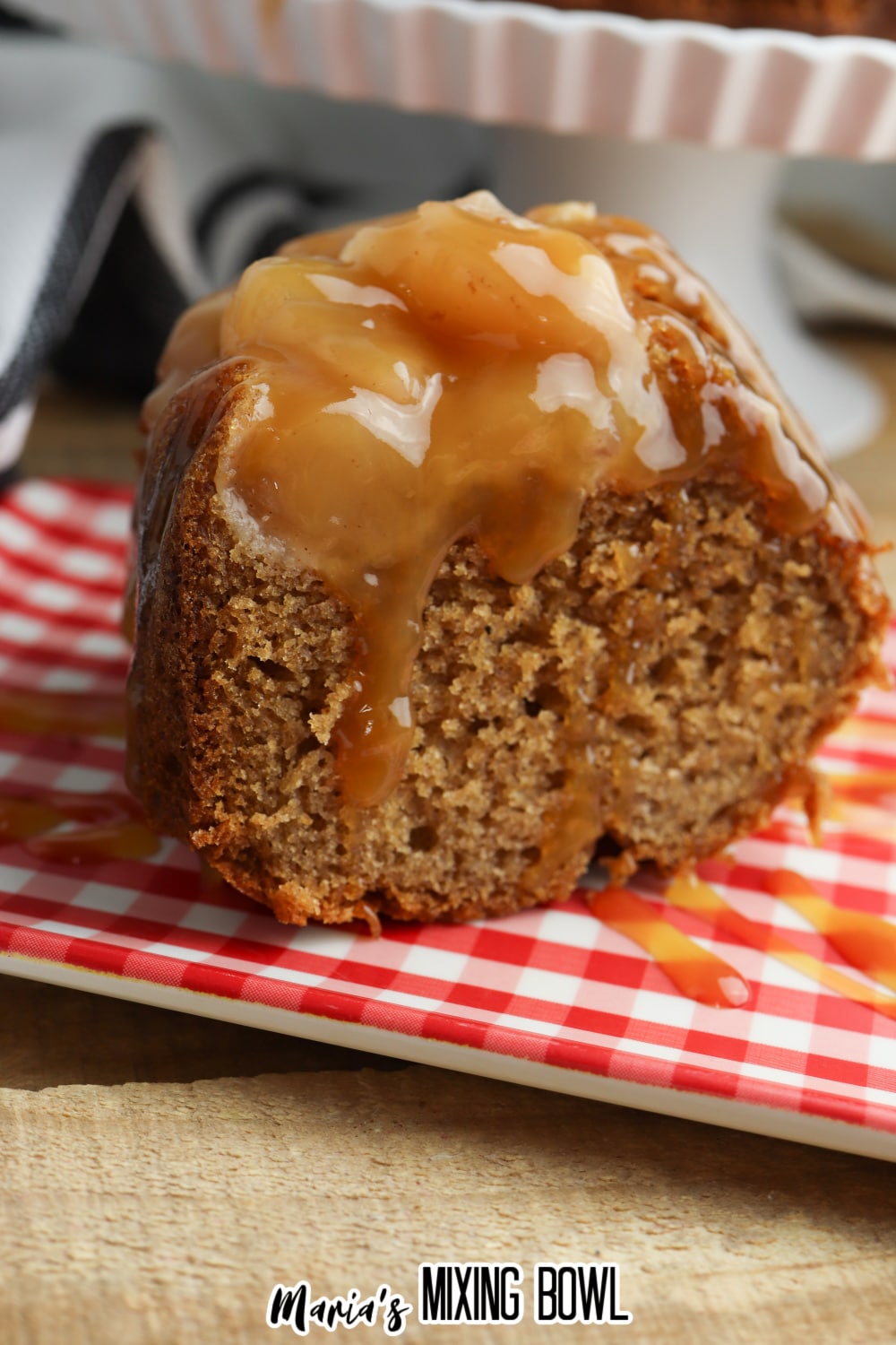 close up of a slice of caramel apple upside down bundt cake on a red and white checkered plate