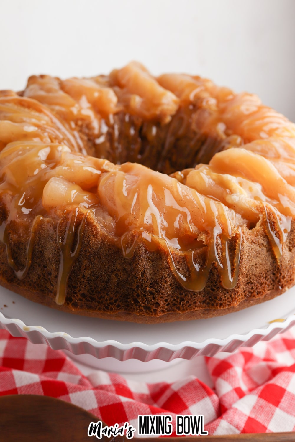 side view of a whole caramel upside down bundt cake on white cake stand
