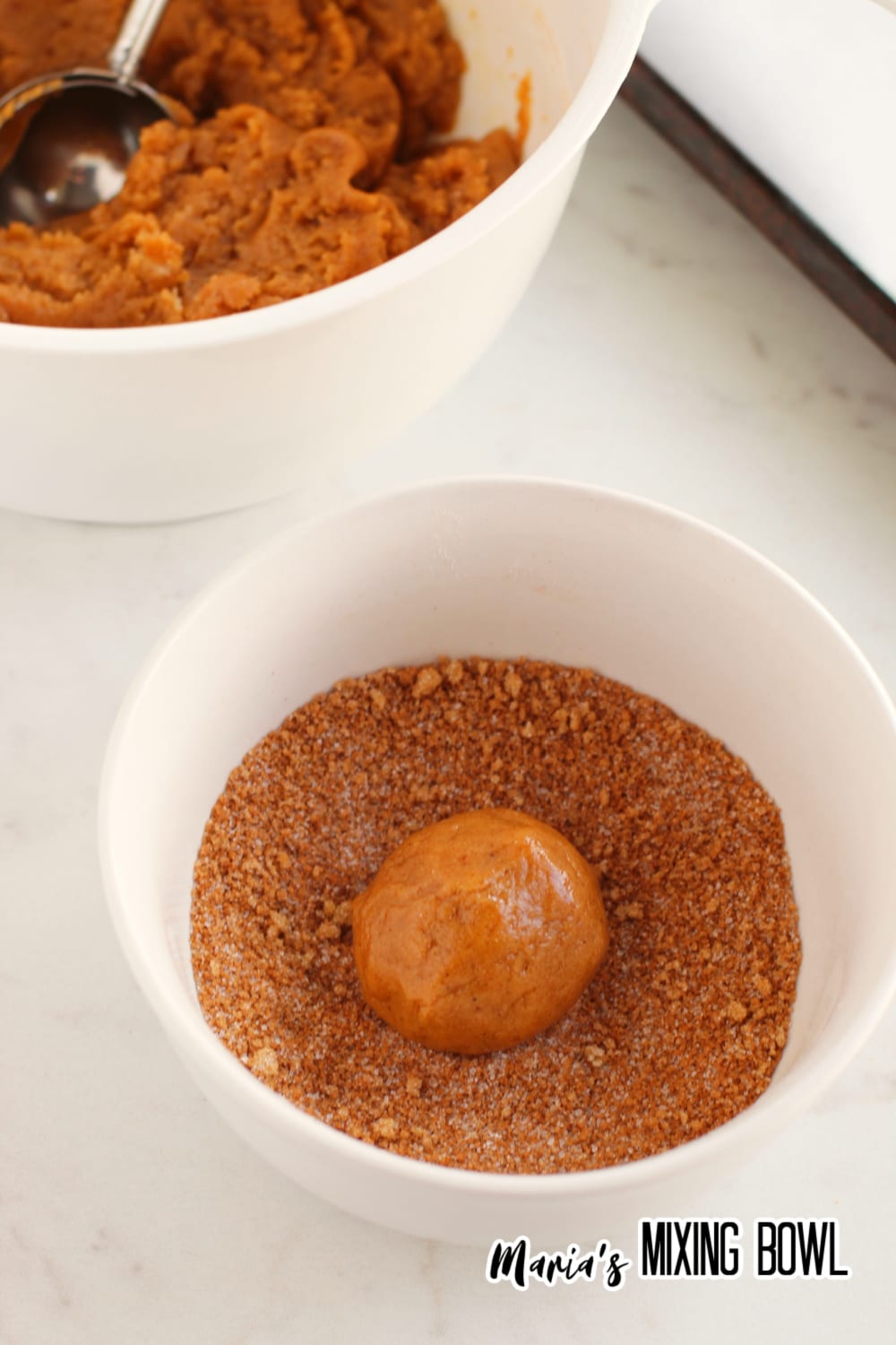 dough ball being rolled in cinnamon sugar mixture
