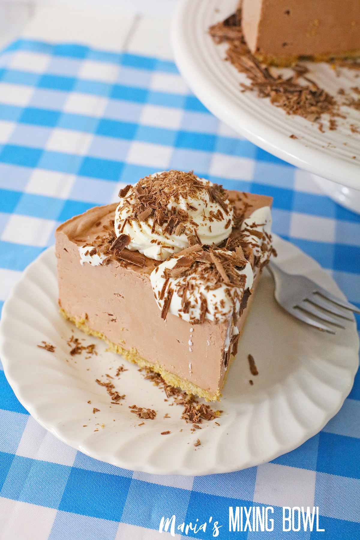 close up of a slice of french silk cheesecake on a white plate with a blue and white napkin