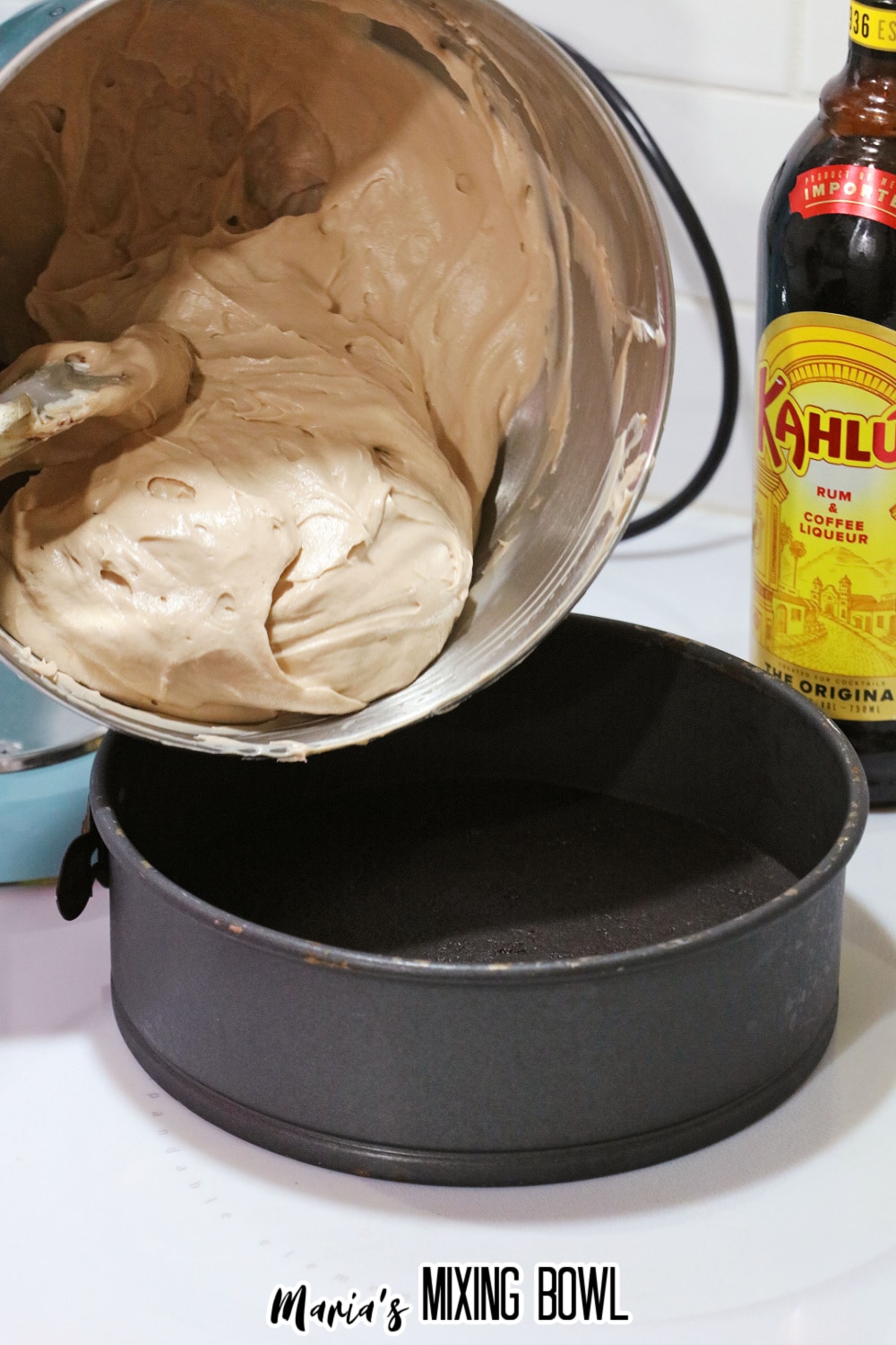 batter being poured into a springform pan lined with oreo cookie crust