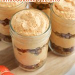 four pumpkin cheesecake parfaits on a wooden cutting board