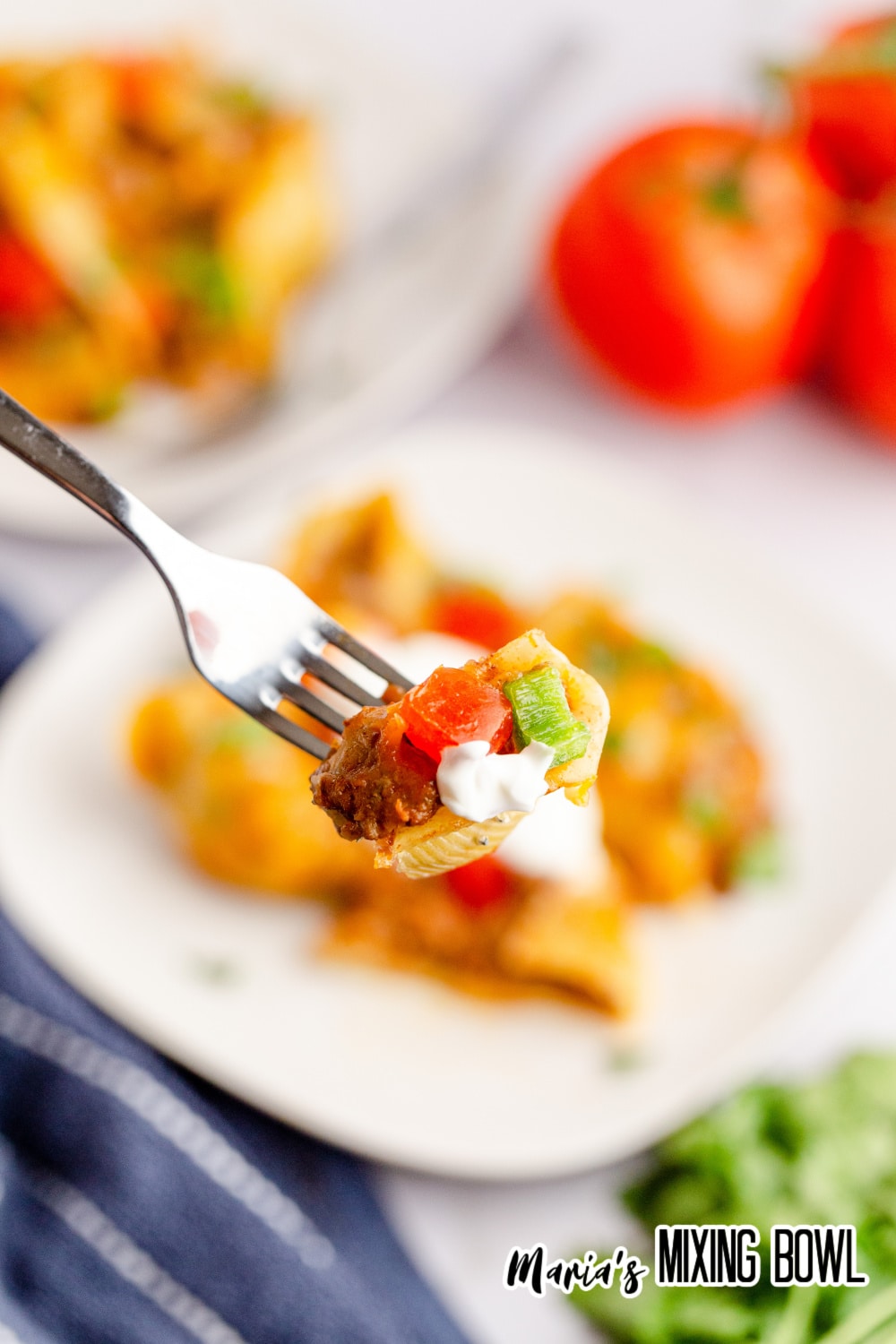 bite of taco pasta shells on a fork held in the air above a plate
