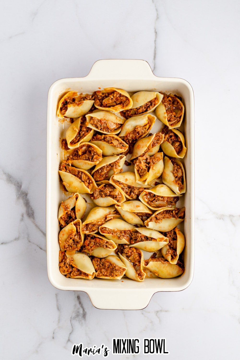 shells stuffed with seasoned ground beef in a lined in a casserole dish