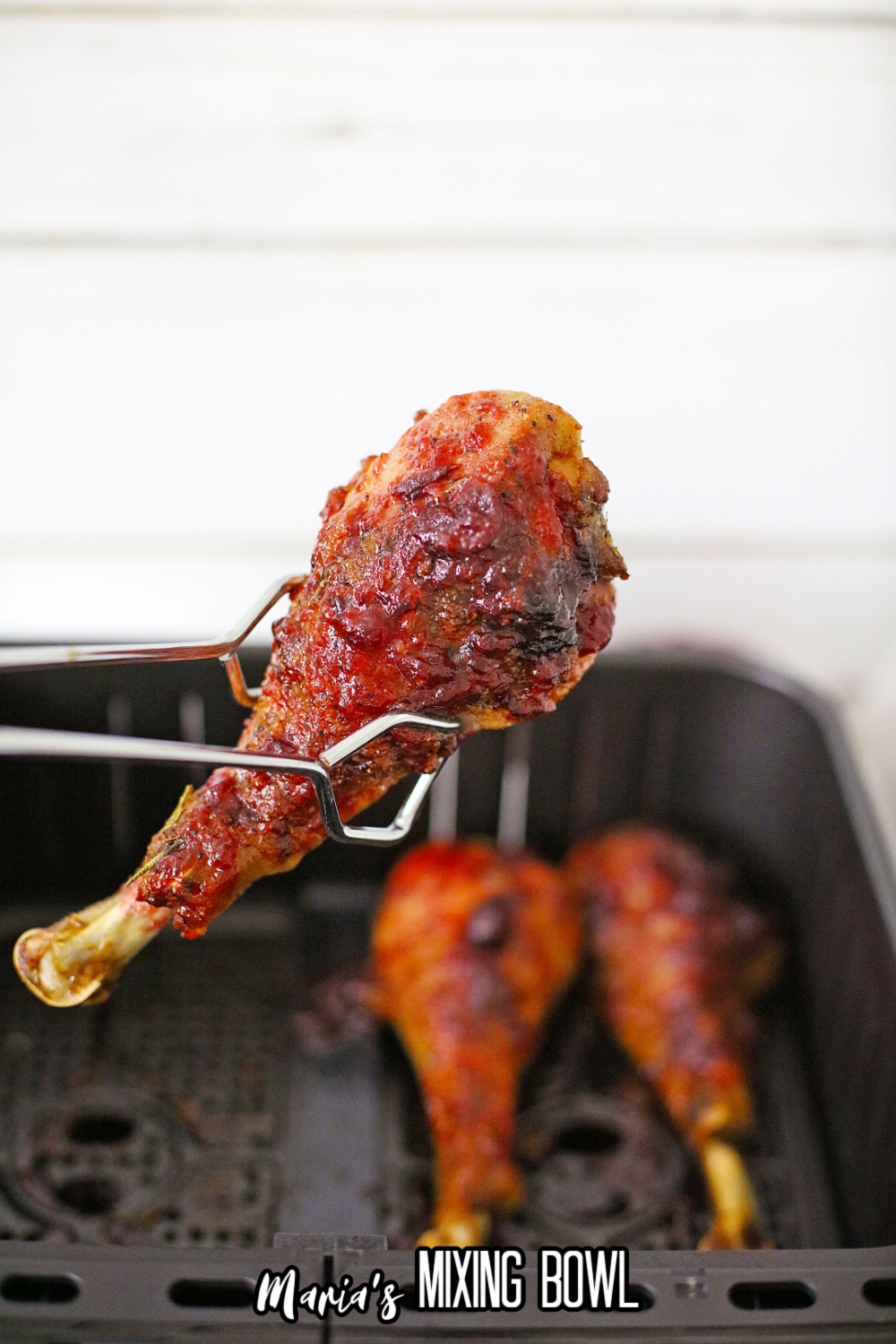 cooked turkey leg held in tongs
