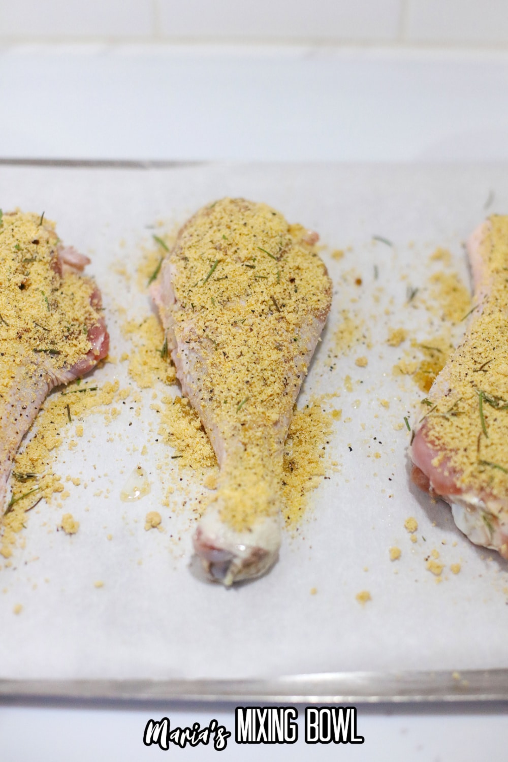 drumsticks topped with seasoning on a parchment lined pan