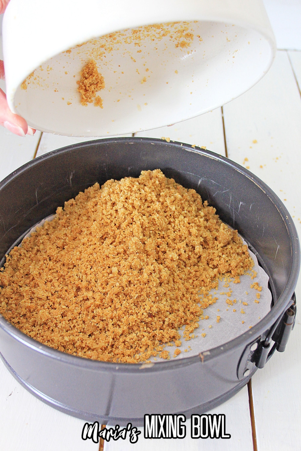 graham cracker crumbs being pressed into a sprinform pan