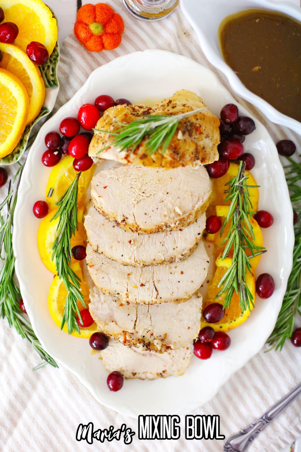 sliced turkey breast on a white plate garnished with oranges and cranberries