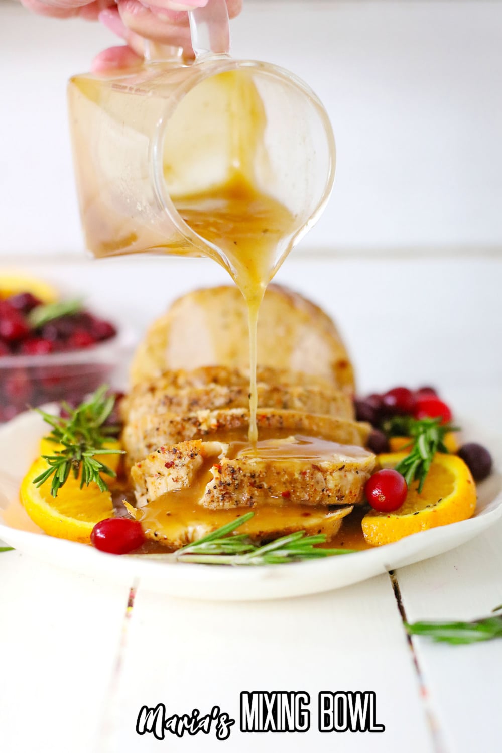 gravy being poured over a turkey breast on a white platter