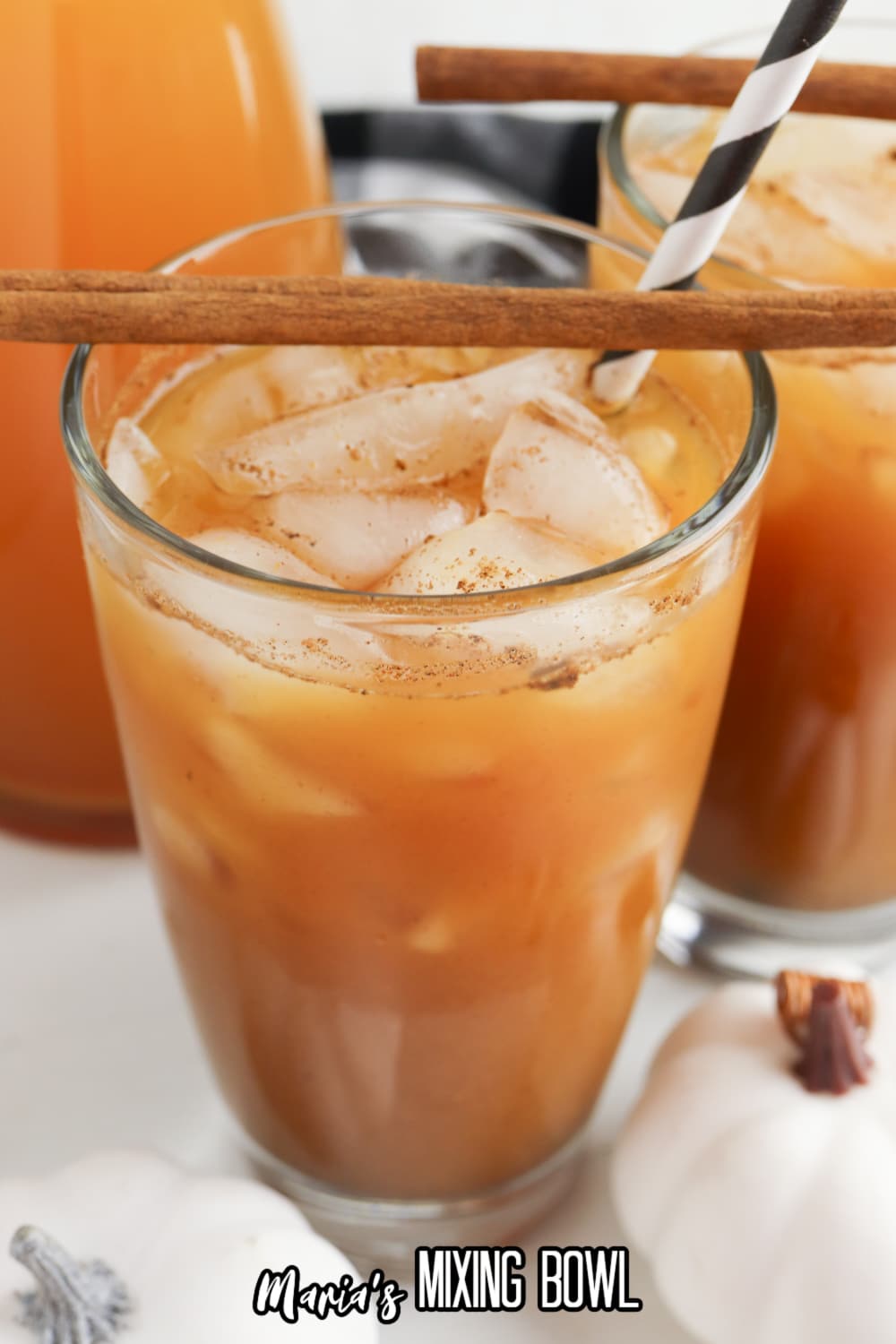 glass of pumpkin juice with a black and white straw and a cinnamon stick on top