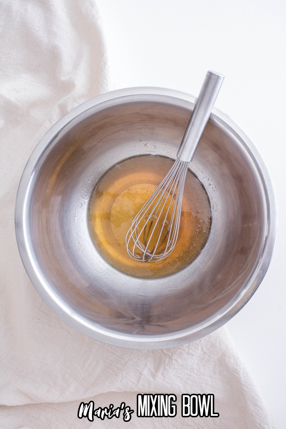 maple syrup and vanilla in a stainless steel mixing bowl with a whisk