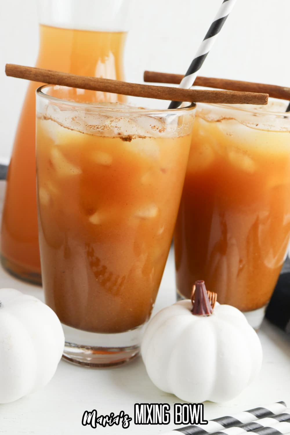 two glasses of pumpkin juice with cinnamon sticks on top