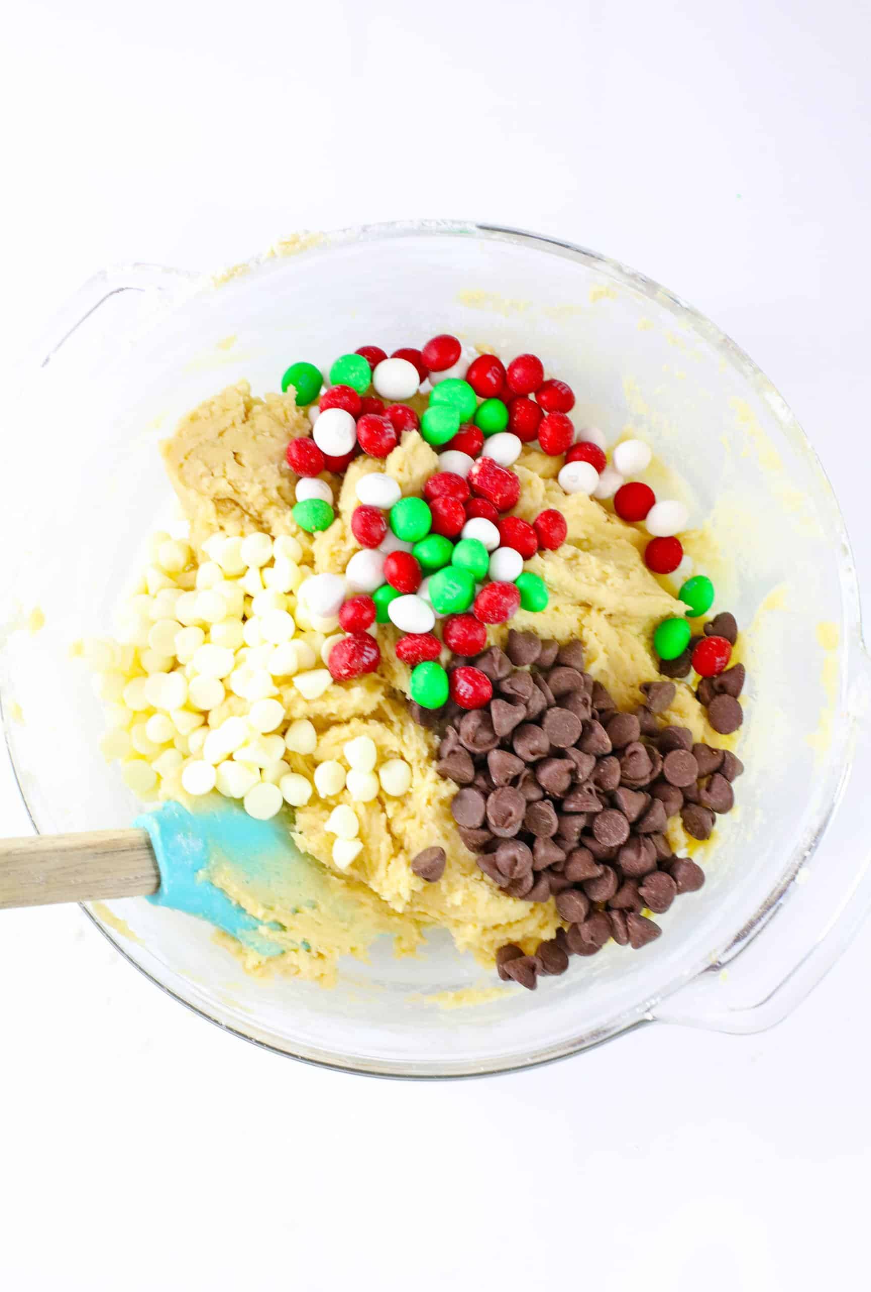 dough, and chocolate chips being stired into a glass mixing bowl