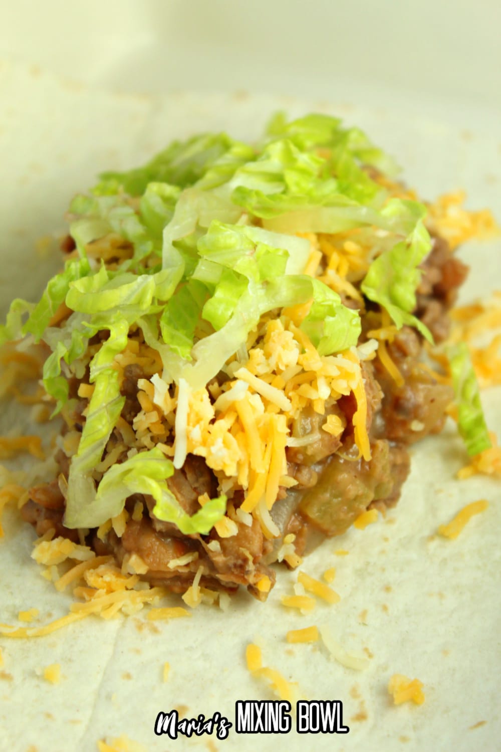 ground beef, beans, cheese, and lettuce on a flour tortilla