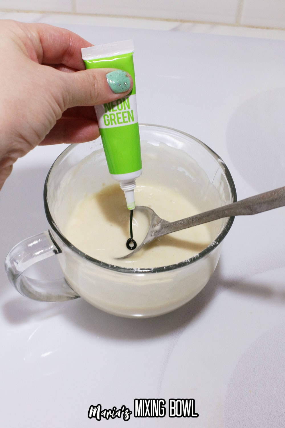 green food coloring being stirred into a coffee cup