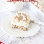 slice of hot cocoa cheesecake bar on a white plate with the name in text for pinterest