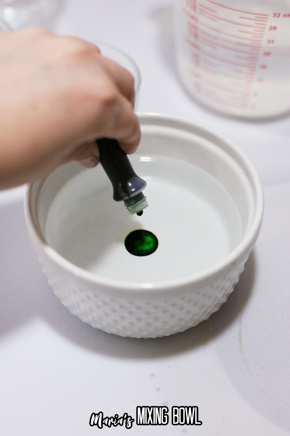 green food coloring being added to a bowl of gelatin