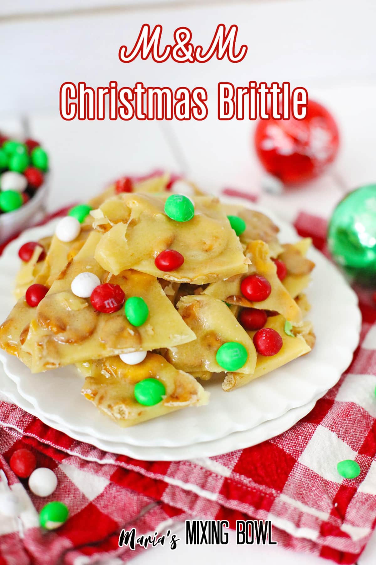 m&m christmas brittle stacked on a white plate with the name in text for pinterest