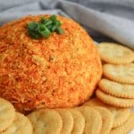 whole nacho cheese ball on a white platter with ritz crackers
