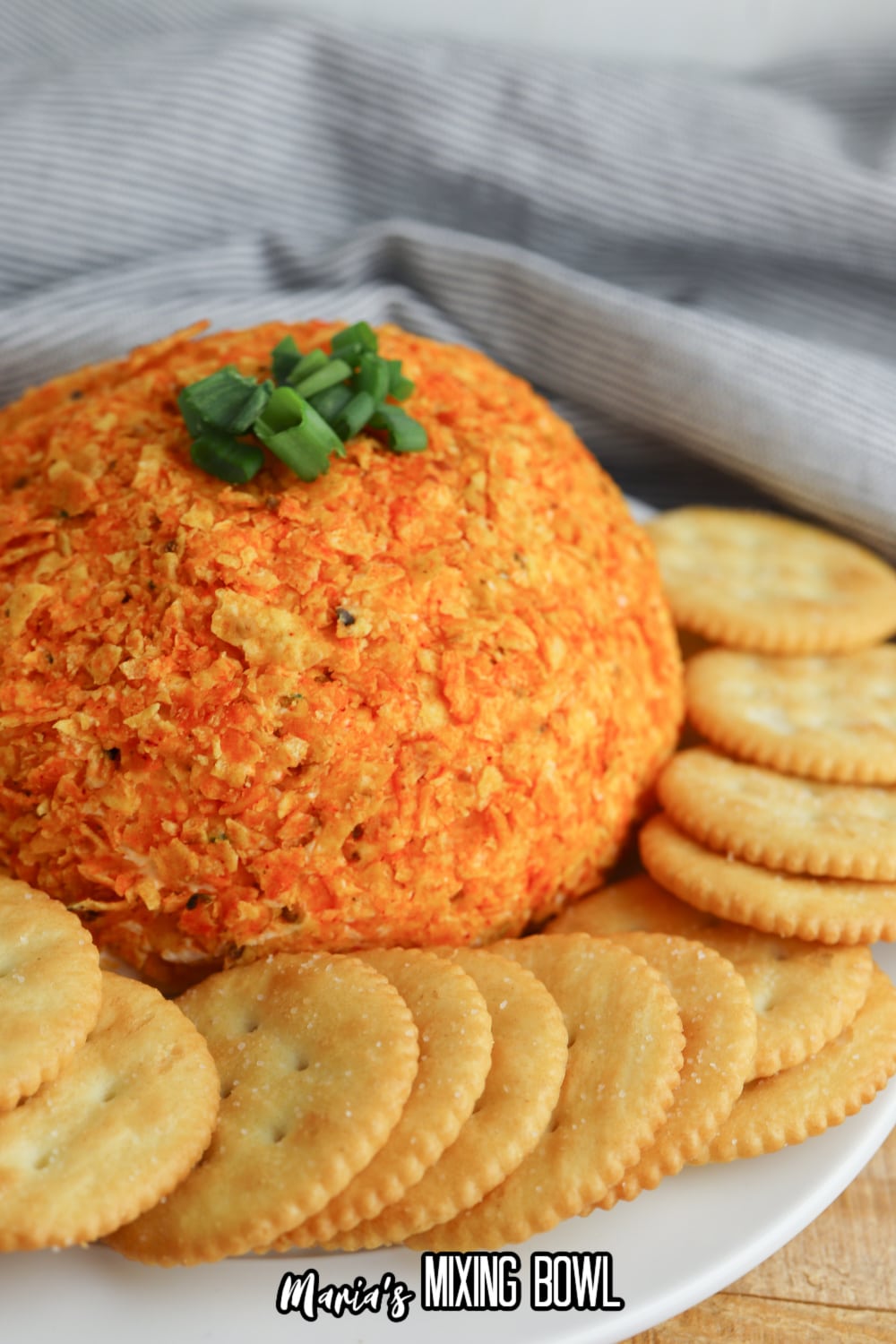 whole nacho cheese ball on a white platter with ritz crackers