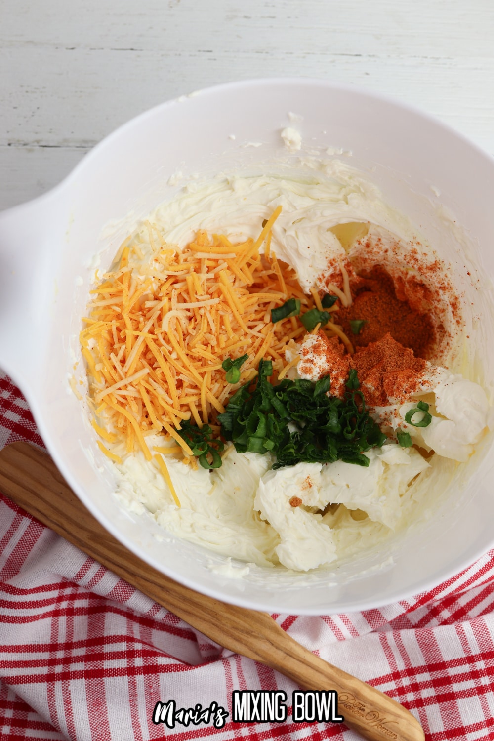cream cheese, cheddar, spices, and green onions in a white mixing bowl