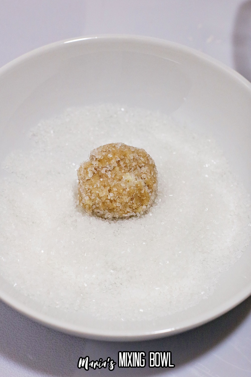 cookie dough ball being rolled in sugar