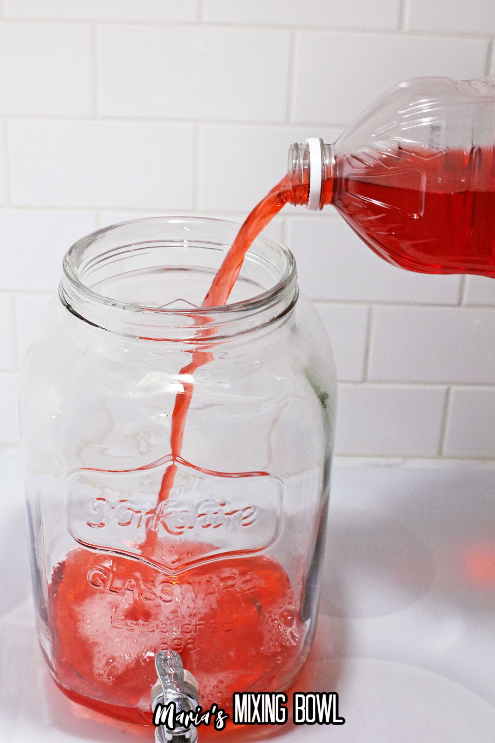 cranberry juice being poured into a mason jar