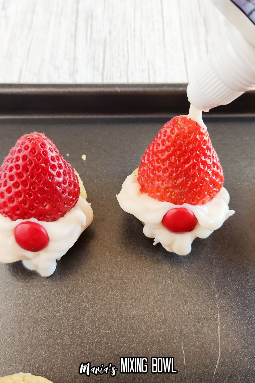 frosting being piped onto the tip of a fresh strawberry