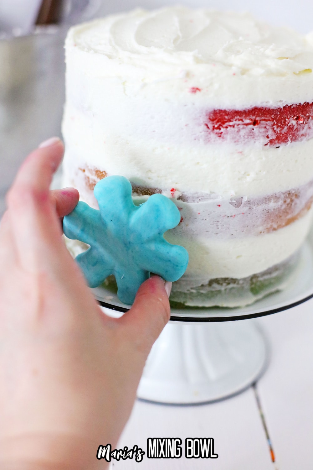 blue snowflake being process onto the cake