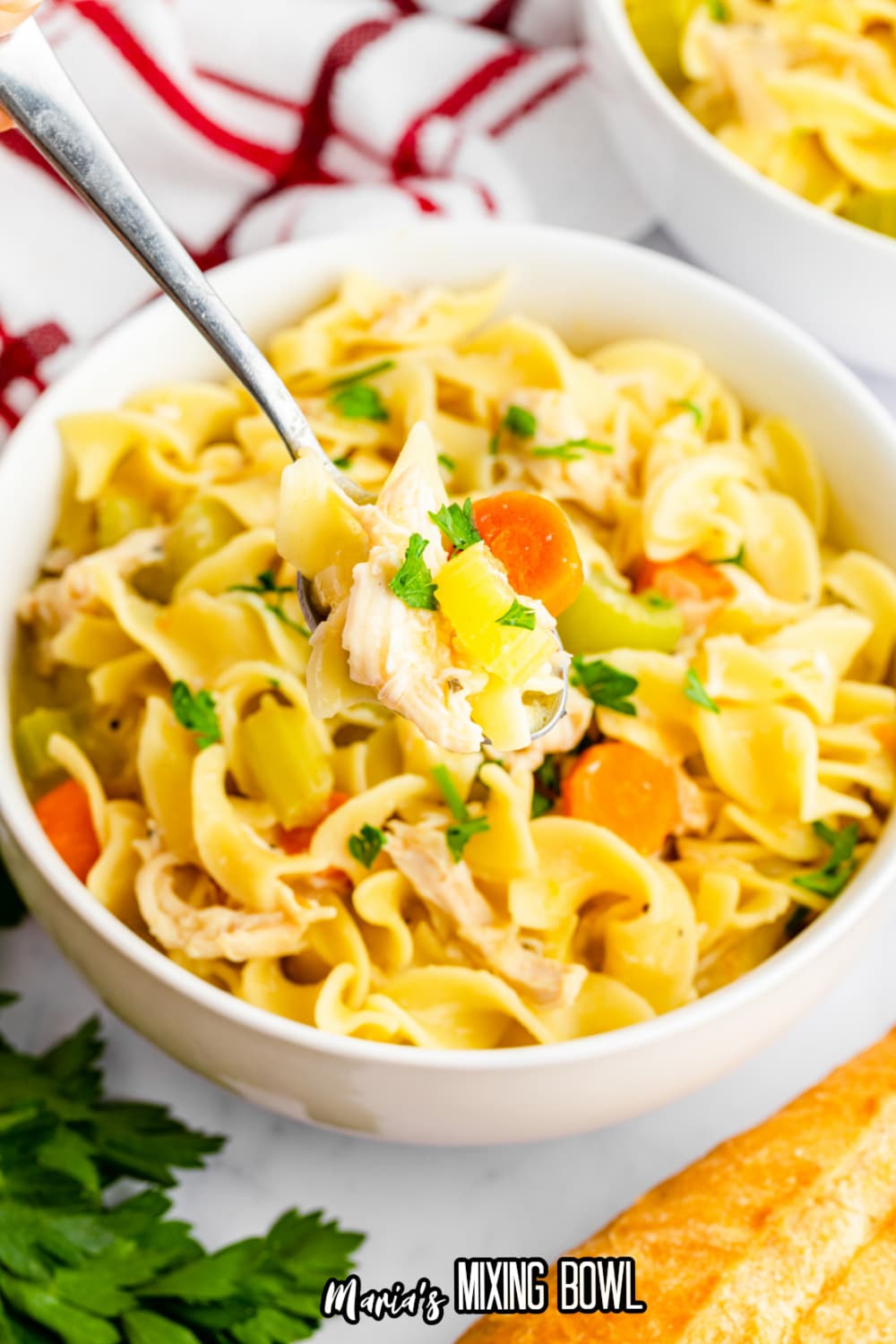 white bowl filled with chicken cafeteria noodles with a bite on a spoon