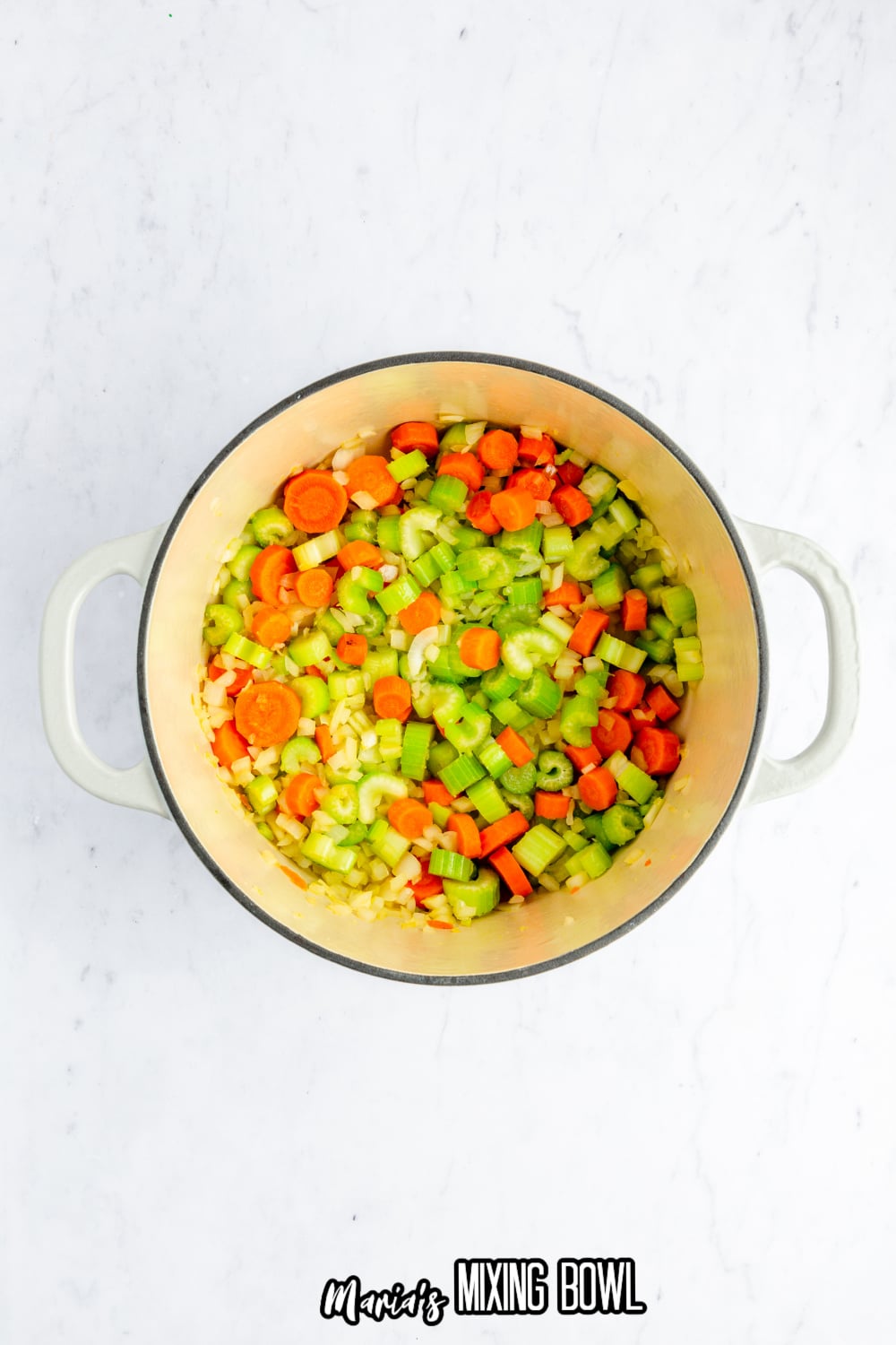 carrots, celery and onions in a white dutch oven