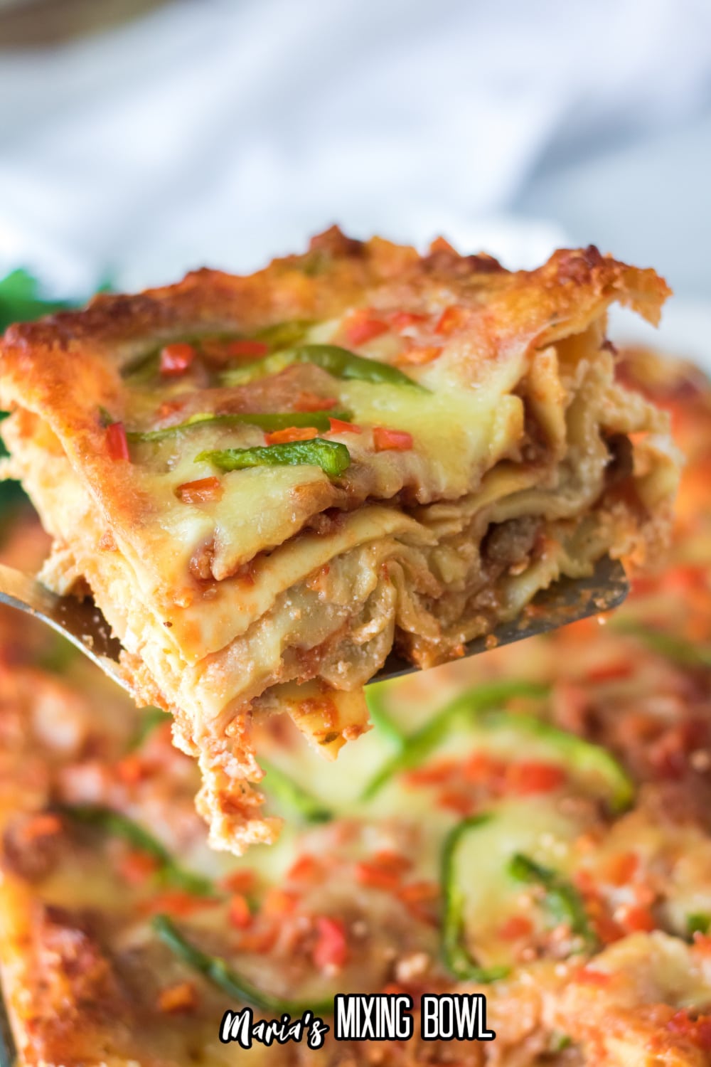 slice of christmas lasagna being held on a metal spatula in the air