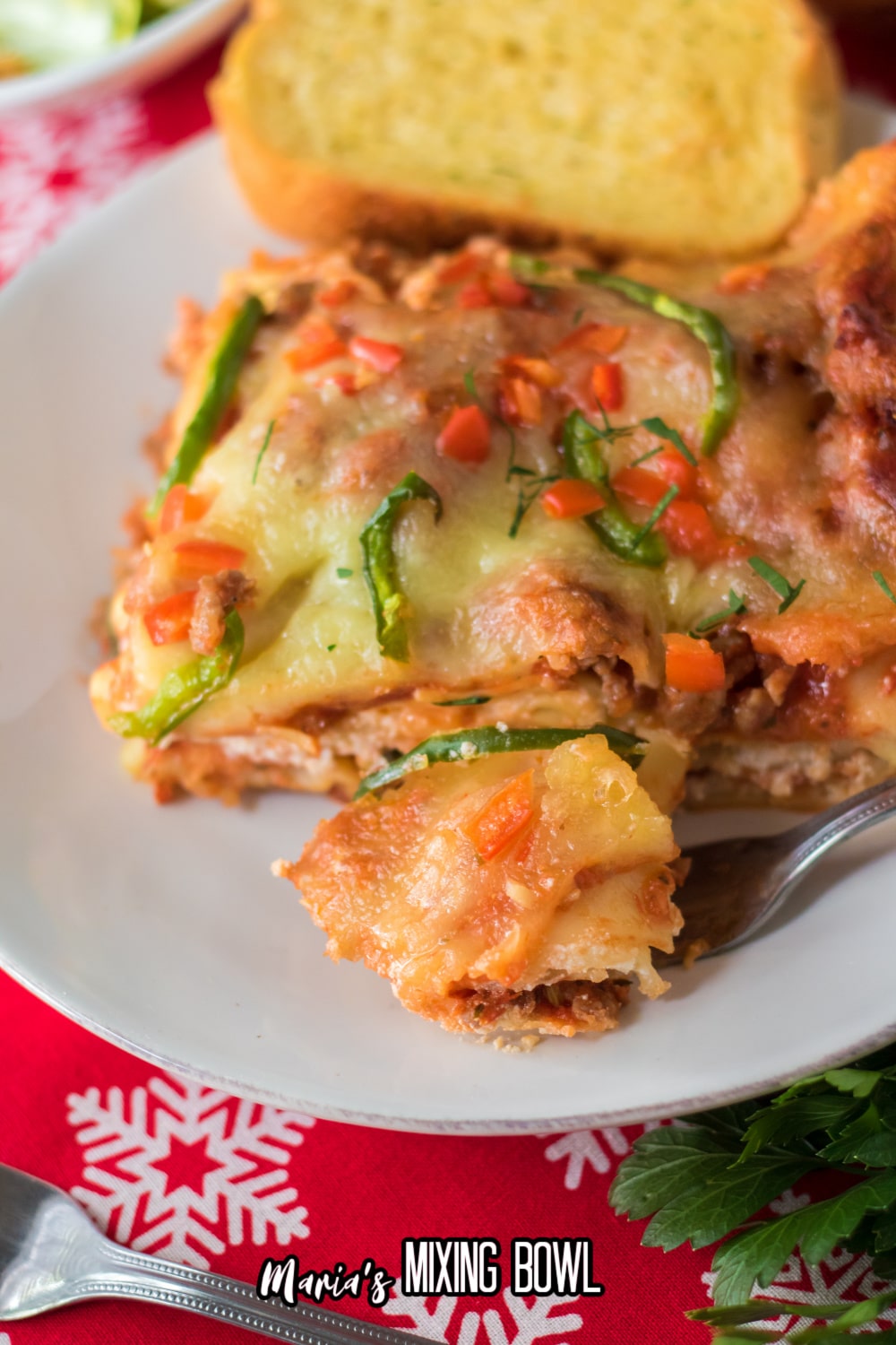 slice of christmas lasagna on a white plaet with a bite on a fork