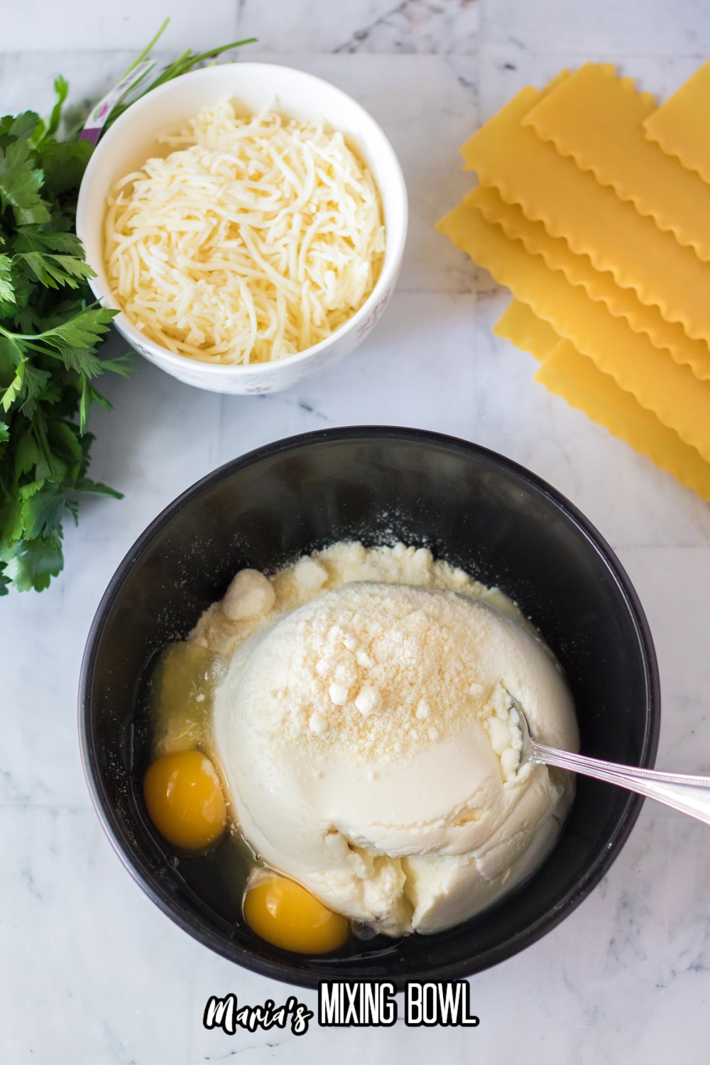 ricotta cheese, eggs, and parmesan chese in a black bowl with a metal spoon