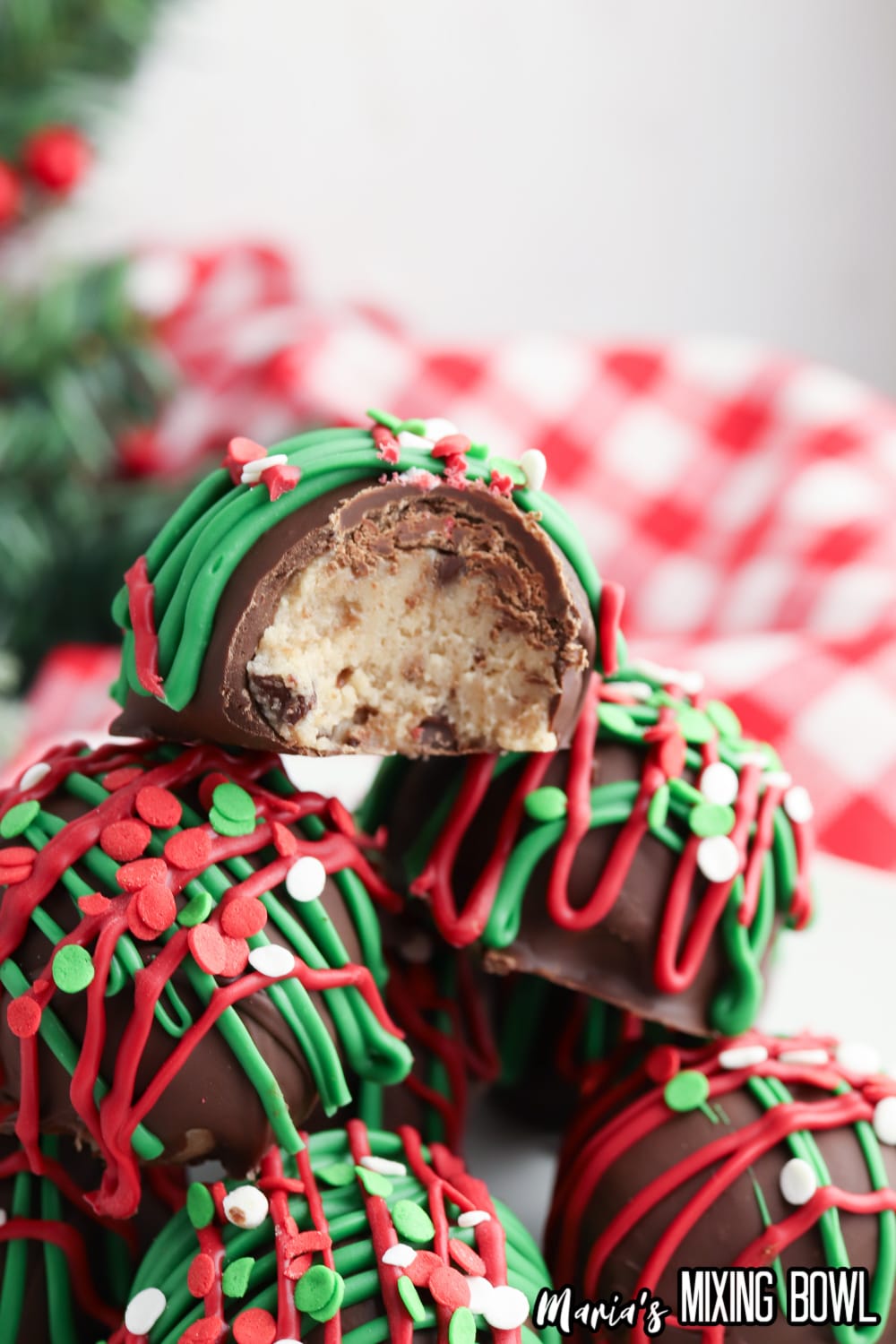 christmas no bake cookie dough bites stacked in a pyramid with the top one bitten in half