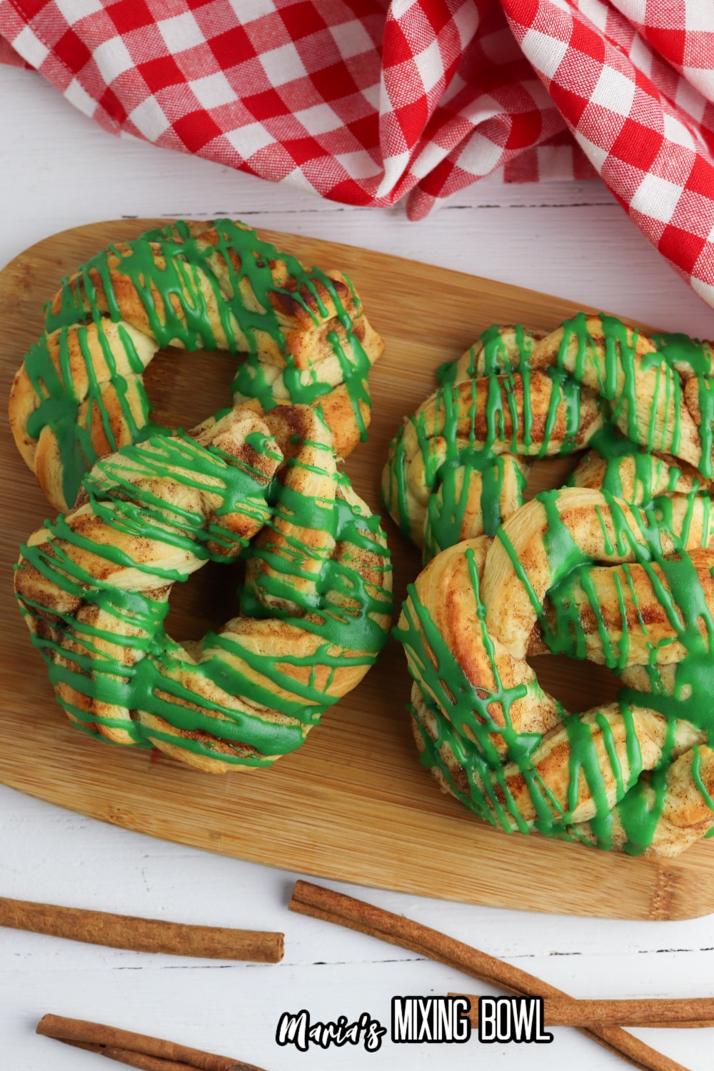 four cinnamon rolls wreaths on a wooden cutting board
