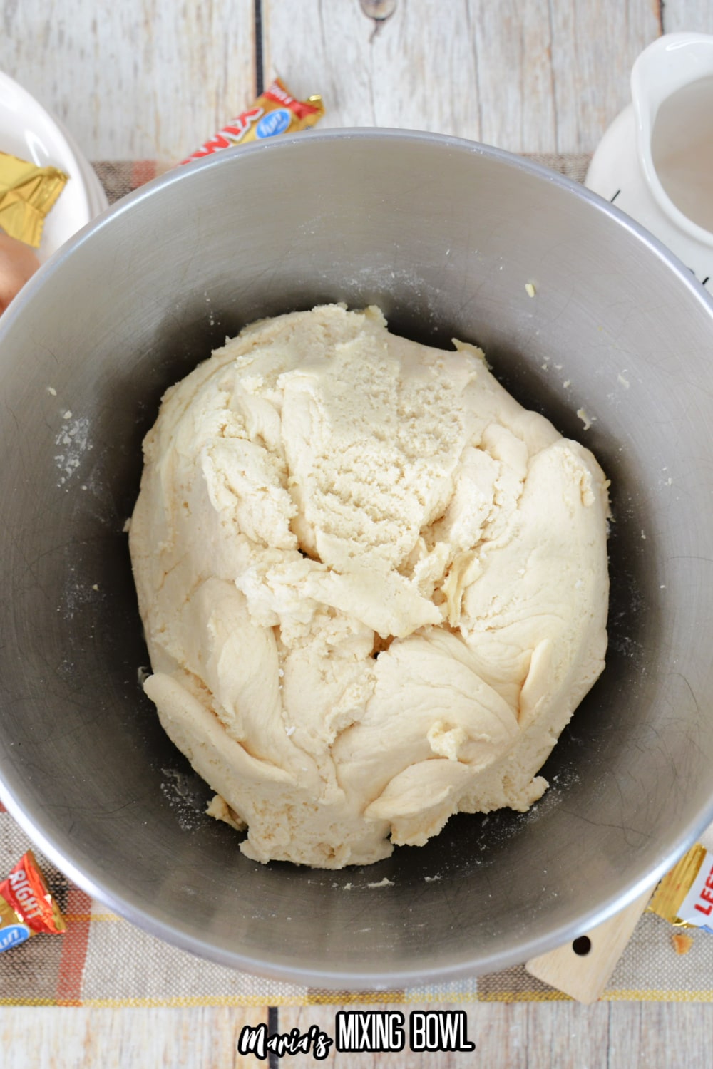 dough in stainless steel mixing bowl on a wooden background