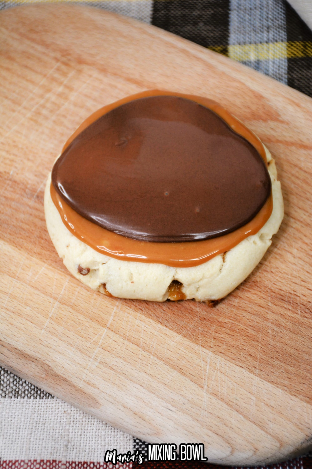 baked cookie being topped with melted caramel and chocolate