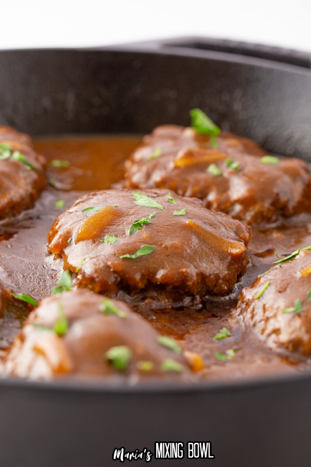 close up of sailsbury steak in a cast iron skillet