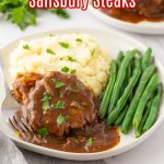 salisbury steaks with green beans and mashed potatoes on a white plate with the name in text for pinterest