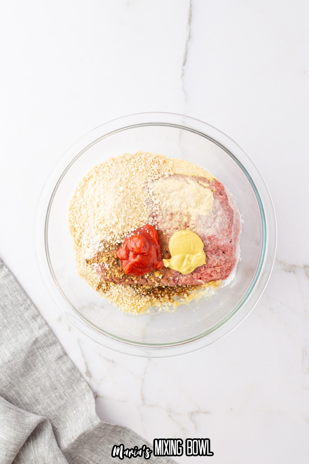 ground beef, breadcrumbs and seasonings in a glass bowl