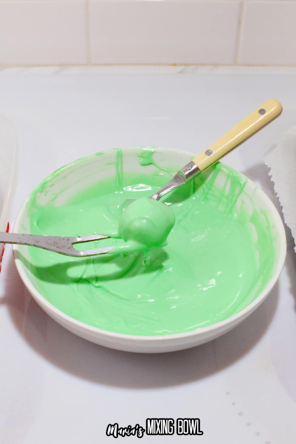 peanut butter ball being dipped in melted green candy melts