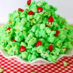 white plate on a red and white kitchen towel filled with grinch popcorn