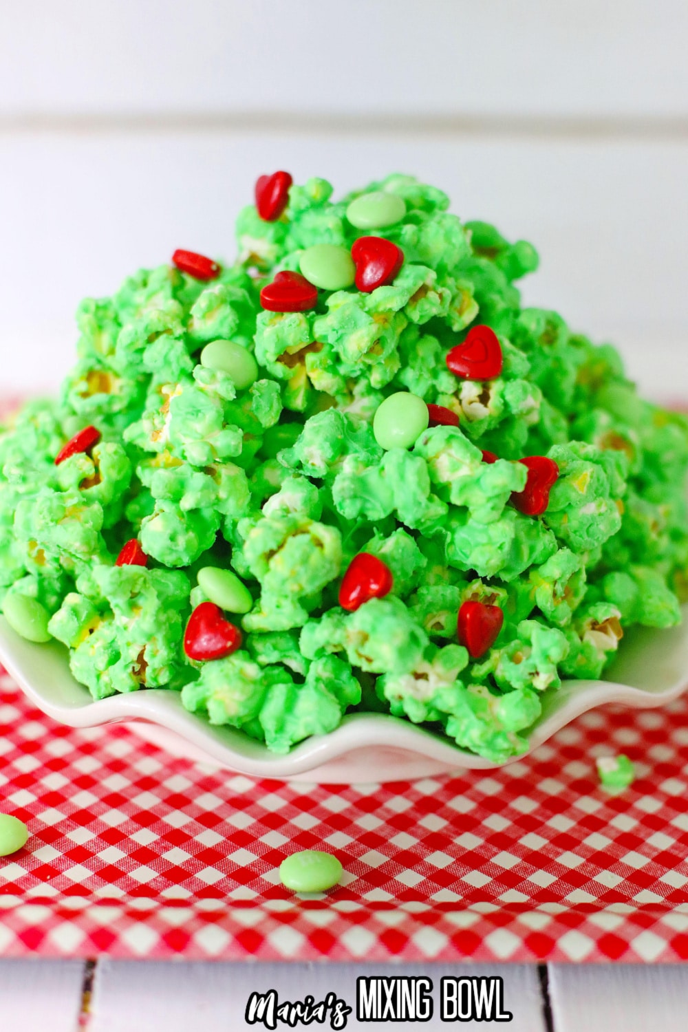 white plate on a red and white kitchen towel filled with grinch popcorn